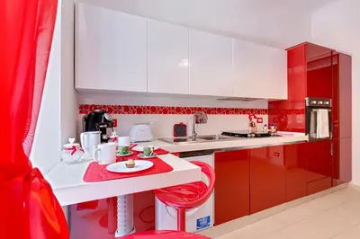 a red and white kitchen with a red chair in it at New In! Sophie at Colosseum in Rome