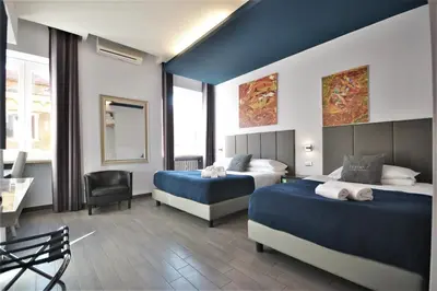 a hotel room with two beds and a desk at B&B Home 77 in Rome