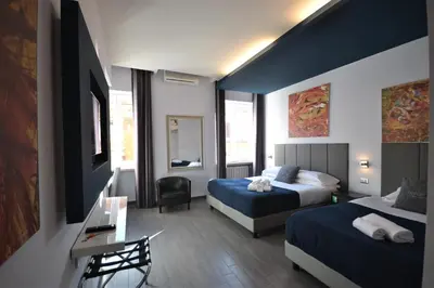 a hotel room with two beds and a flat screen tv at B&B Home 77 in Rome