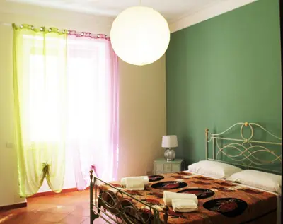 a bedroom with a bed with green walls and a large window at A Casa Di Magda (Al centro di Roma) in Rome