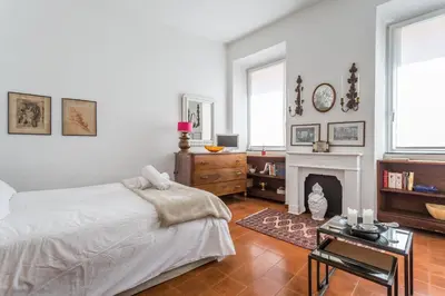 a white bedroom with a bed and a fireplace at Sora Menica in Rome