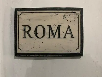 a sign that says roma hanging on a wall at Italy Guest House in Rome