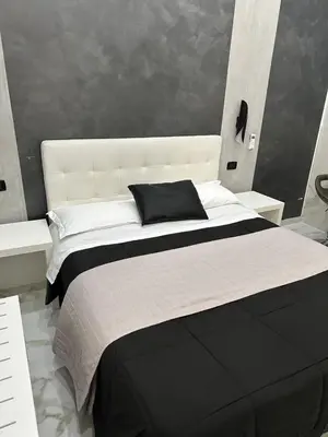 a large white bed with a black pillow on it at Italy Guest House in Rome