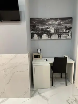 a white desk with a chair and a picture on the wall at Italy Guest House in Rome