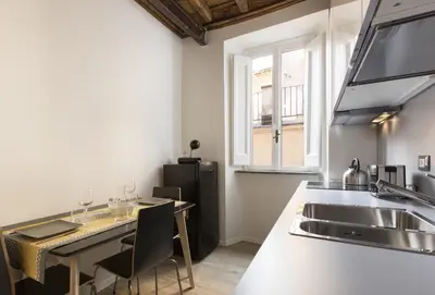 a kitchen with a sink and a table with chairs at Cozy apartment in via degli Spagnoli - FromHometoRome in Rome