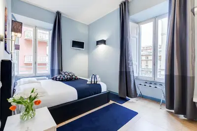 a bedroom with a bed with blue walls and windows at Easy Budget Colosseo in Rome