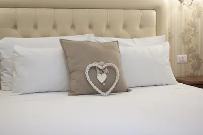 a heart pillow on a bed with white pillows at Suite Dal Conte in Rome