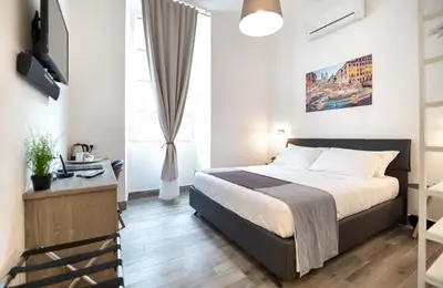 a bedroom with a bed and a desk and a window at Clementi 18 Suites Rome in Rome