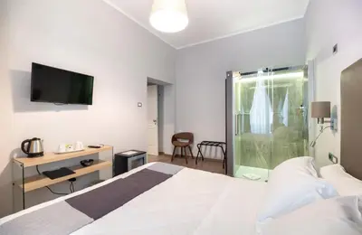 a bedroom with a bed and a desk and a television at Clementi 18 Suites Rome in Rome