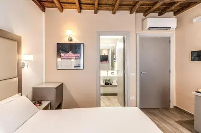 a bedroom with a white bed and a bathroom at Reginella Suites in Rome
