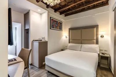 a bedroom with a white bed and a desk and a chair at Reginella Suites in Rome