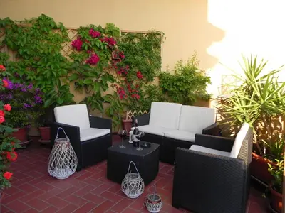 a patio with white chairs and tables and flowers at Terrazza 29 Holiday Home in Rome