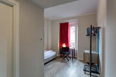 a bedroom with a bed and a desk and a window at MEININGER Roma Termini in Rome