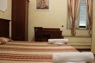 a bedroom with a bed and a desk and a window at Affittacamere Alex in Rome