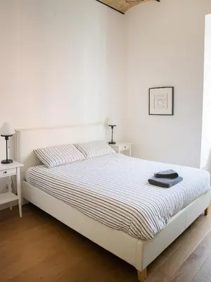 a bed in a white room with two tables at Domus Claudi Colosseum in Rome