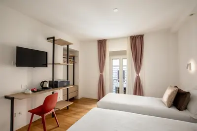 a hotel room with two beds and a red chair at Hotel Ciao in Rome