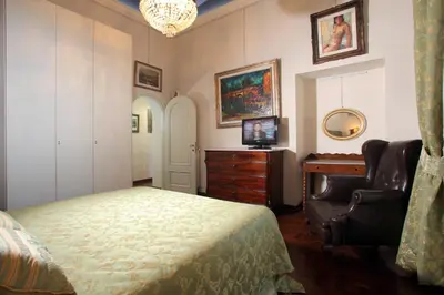 a bedroom with a bed and a chair and a television at Appartamento d'epoca Colosseo Art Gallery in Rome
