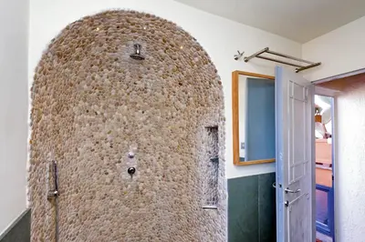 a bathroom with a shower with a stone wall at Vicolo del Cinque Penthouse | Romeloft in Rome