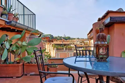 a blue table and chairs on a balcony with plants at Vicolo del Cinque Penthouse | Romeloft in Rome