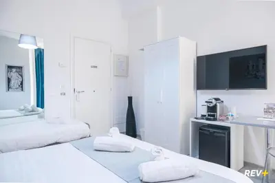 a white room with two beds and a tv at Viale Giulio Cesare Guest House in Rome
