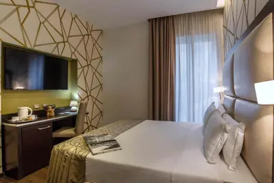 a hotel room with a bed and a desk and a television at Catone District Hotel in Rome