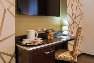 a room with a desk and a chair with a plate of food at Catone District Hotel in Rome