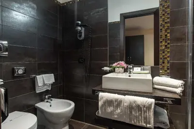 a bathroom with a sink and a toilet and a mirror at Catone District Hotel in Rome
