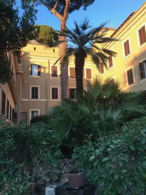 a building with palm trees and bushes in front of a building at Villa Angelina in Rome