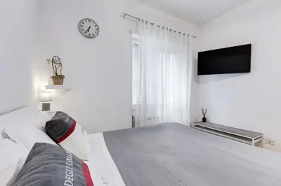 a white bedroom with a bed and a clock on the wall at Vatican 96 Degli Ubaldi Studio steps from metro and St Peter's in Rome
