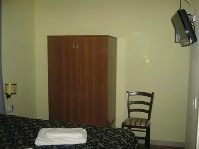 a bedroom with a bed and a chair and a cabinet at Hotel Ferraro in Rome