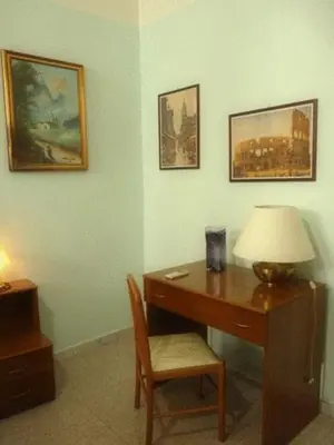 a desk with a lamp and a chair next to a table at Hotel Ferraro in Rome