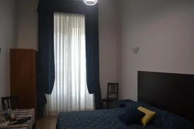 a bedroom with a bed and a window with blue curtains at Incantoromano guest house in Rome