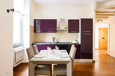 a kitchen with a table with chairs and purple cabinets at The Royal Story in Rome