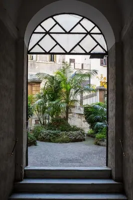 an archway with stairs leading to a courtyard with palm trees at The Royal Story in Rome