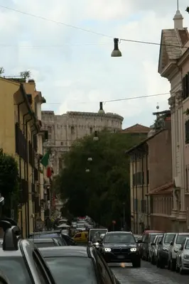 a city street with cars parked on the street with a building at La Romàntìca al Colosseo in Rome