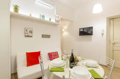 a dining room with a white table and a white couch at La Romàntìca al Colosseo in Rome