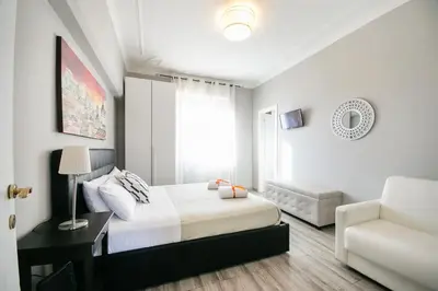 a white bedroom with a bed and a chair at San Peter Raffy's House in Rome