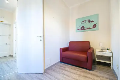a room with a red chair and a painting of a car on the wall at San Peter Raffy's House in Rome