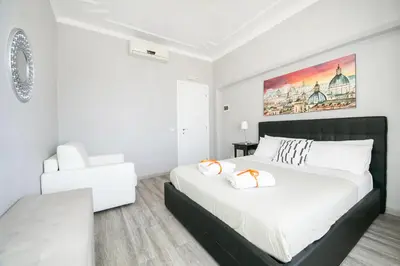 a white bedroom with a large bed and a chair at San Peter Raffy's House in Rome
