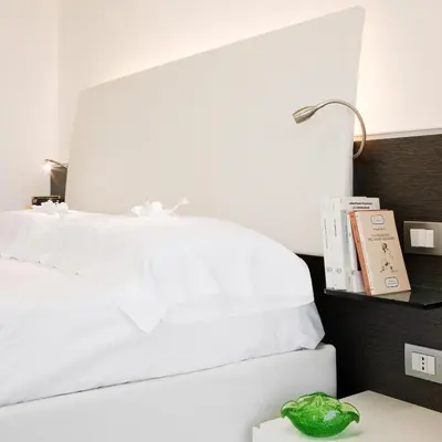 a bed with white sheets and a lamp on a table at Lungotevere Suite in Rome