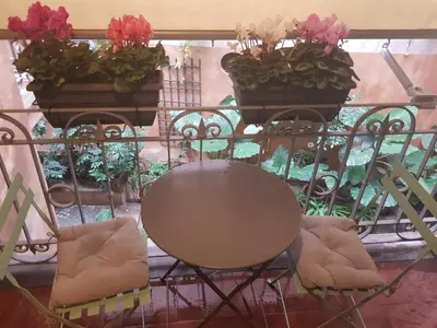 a table and chairs on a balcony with flowers at Foro Romano Luxury Suites in Rome