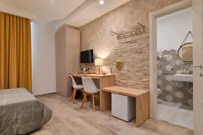 a hotel room with a desk and a bedroom at Veneto Suite Rome in Rome