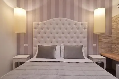 a bedroom with a large bed with a large headboard at Veneto Suite Rome in Rome