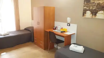 a small room with a desk and a bed and a bed and a deskicter at Piumith Guest House in Rome