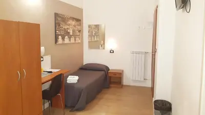 a small bedroom with a bed and a desk at Piumith Guest House in Rome