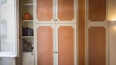 a white cabinet with brown doors next to a book shelf at Leutari Suite in Rome