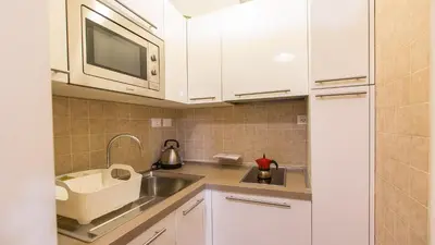 a kitchen with white cabinets and a sink and a microwave at Leutari Suite in Rome