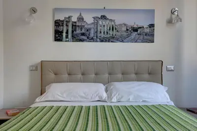 a bedroom with a bed with a green and white blanket at La Casa Sui Fori in Rome