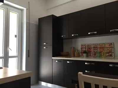 a kitchen with black cabinets and a table at BenS'Houses - Villa Pamphili apartment in Rome