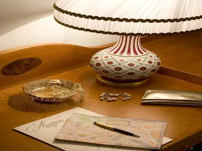 a lamp sitting on a table with a book and a pen at Hotel Aberdeen in Rome